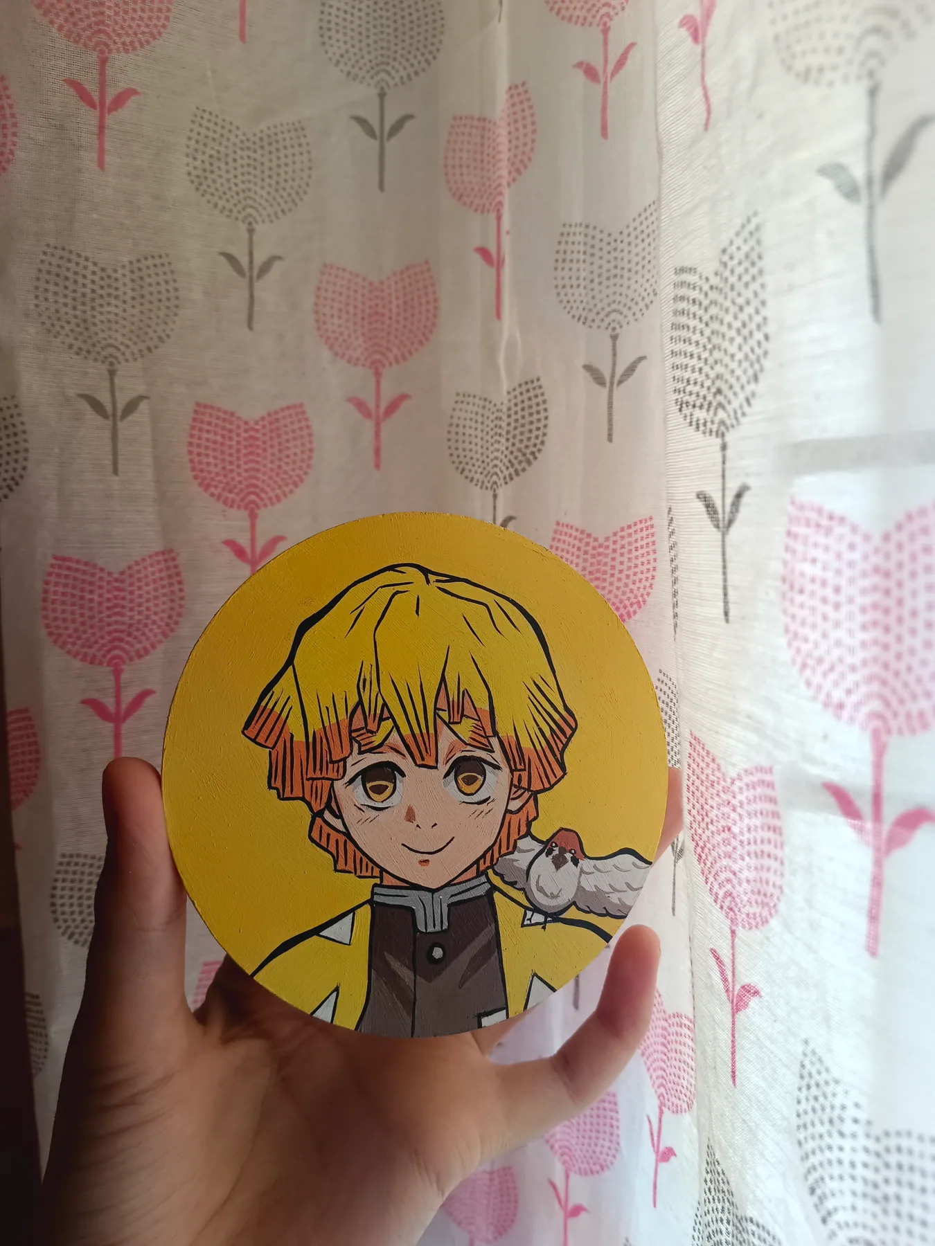 Hand-painted acrylic round mini canvas of Zenitsu Agatsuma from Demon Slayer in yellow tones, held against patterned curtains.