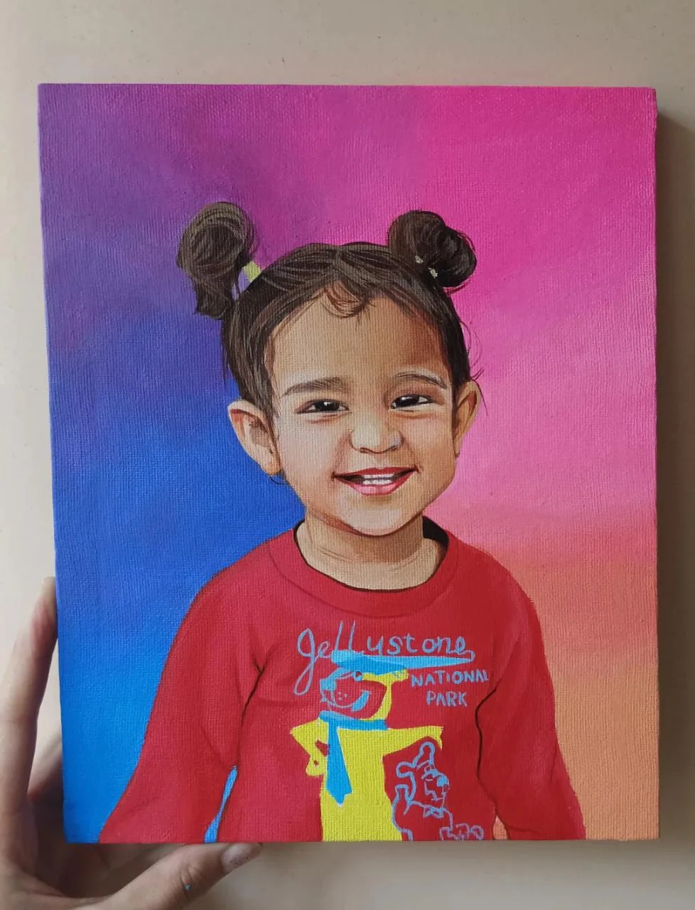 Custom child portrait painting on canvas with a bright pink and blue background, held in hand as a commission sample.