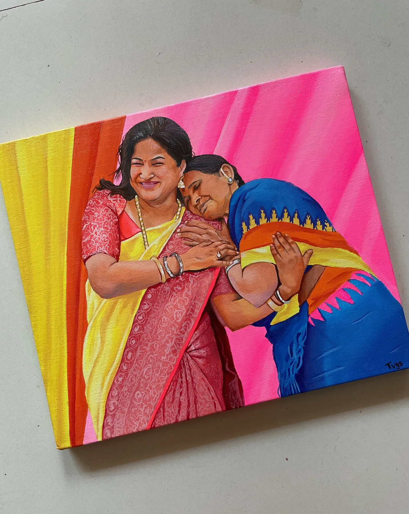 Colourful family portrait painting of two women in sarees, with a warm striped background and affectionate pose.