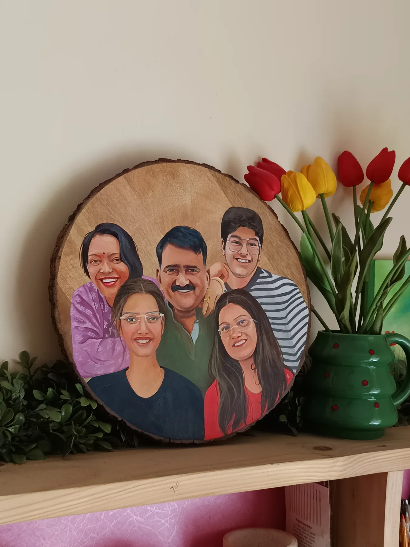 Round wood slice family portrait of five smiling people, displayed beside tulips as a personalised handmade gift.