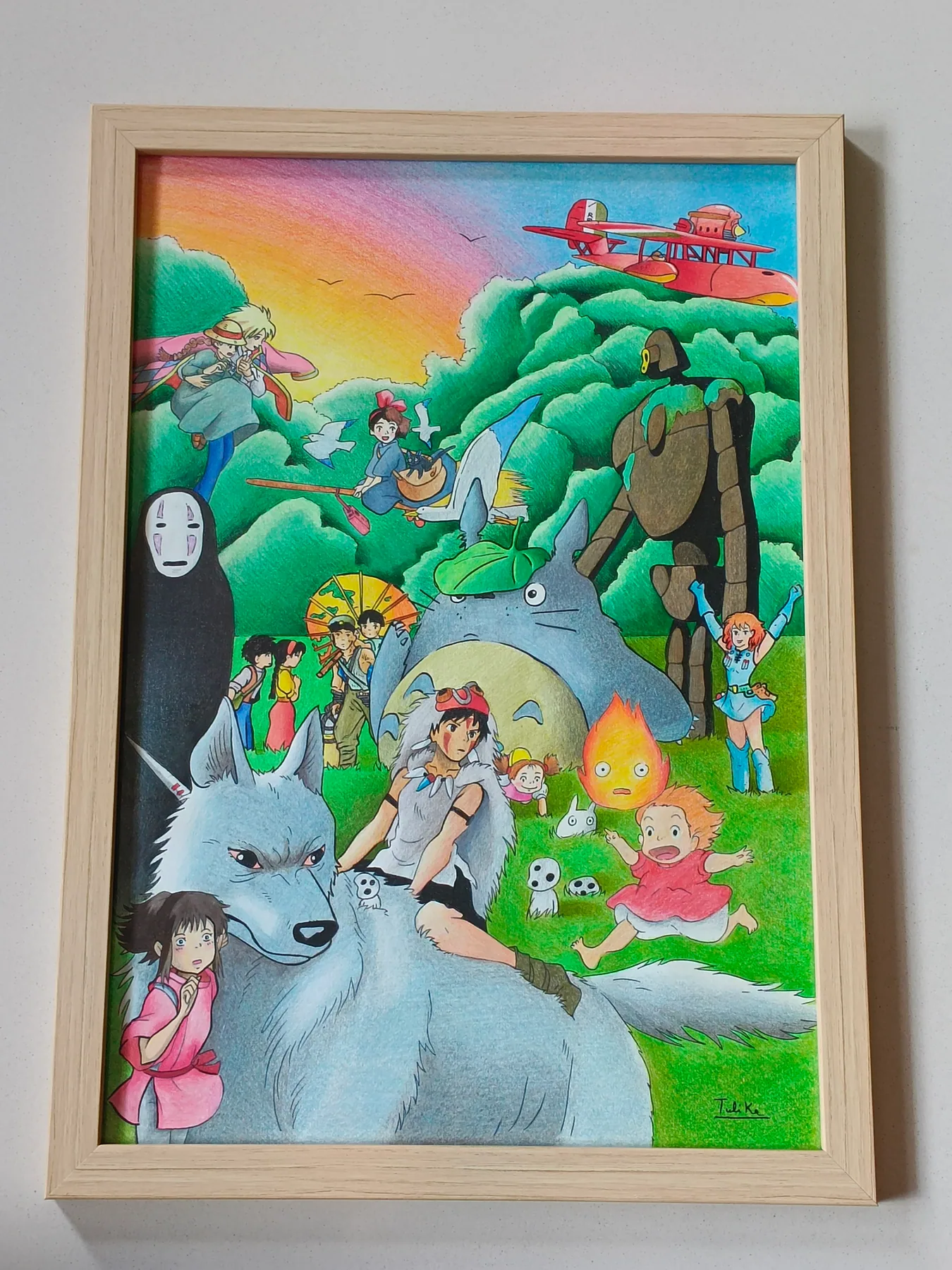 Framed colour-pencil fantasy landscape with Studio Ghibli-style characters, green hills and a soft rainbow sky.