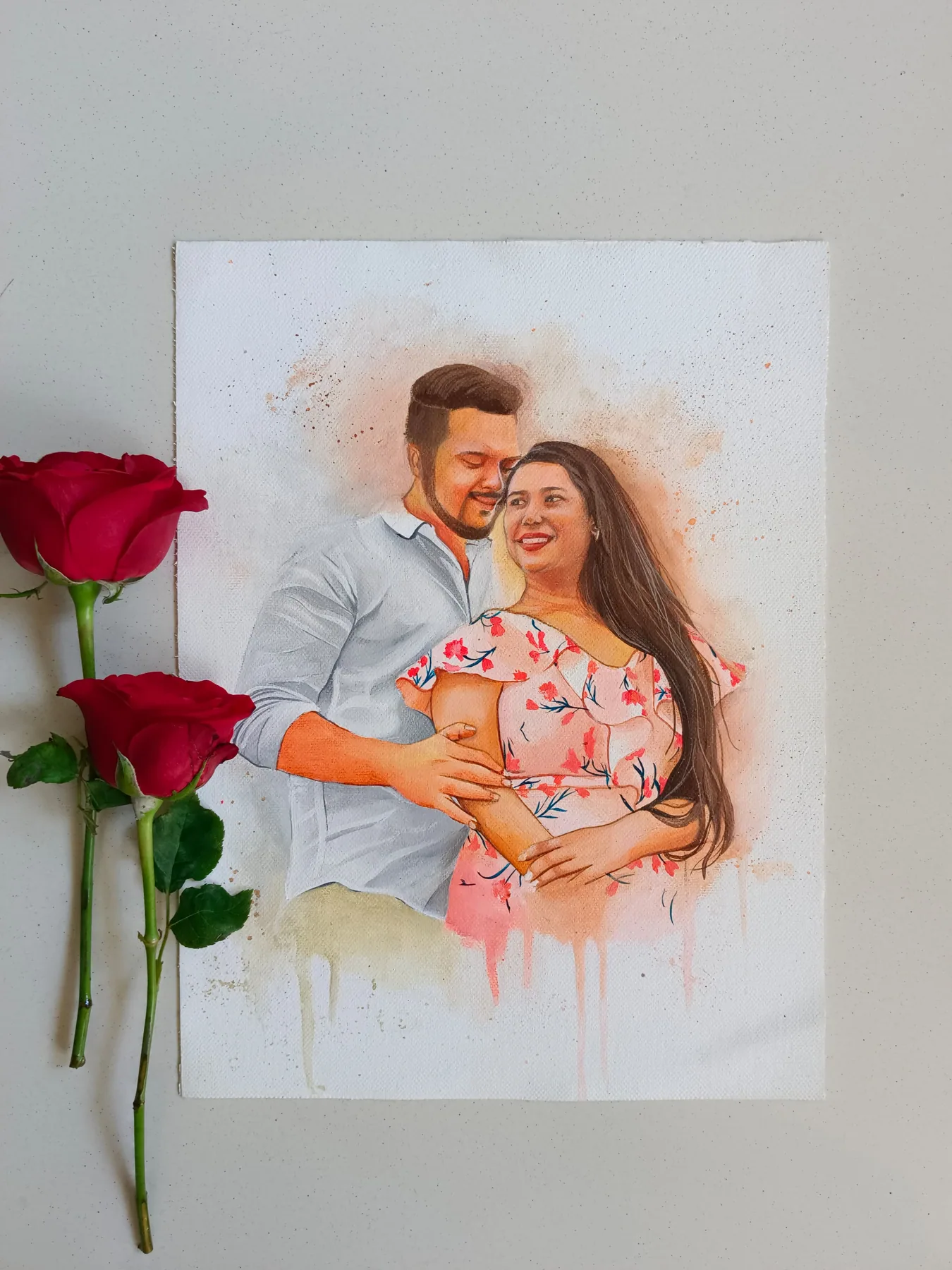 Soft romantic portrait of a couple with a baby, painted with warm peach tones and displayed beside red roses.